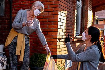 volunteer passing groceries to a mature woman